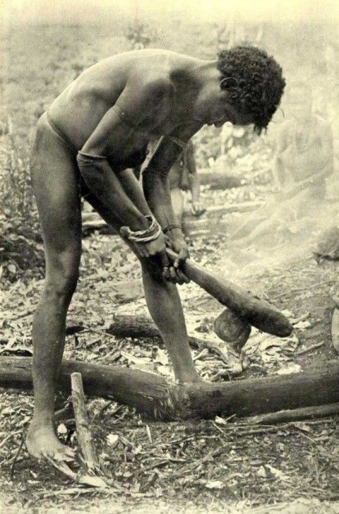 Молодой человек рубит ствол каменным топором
