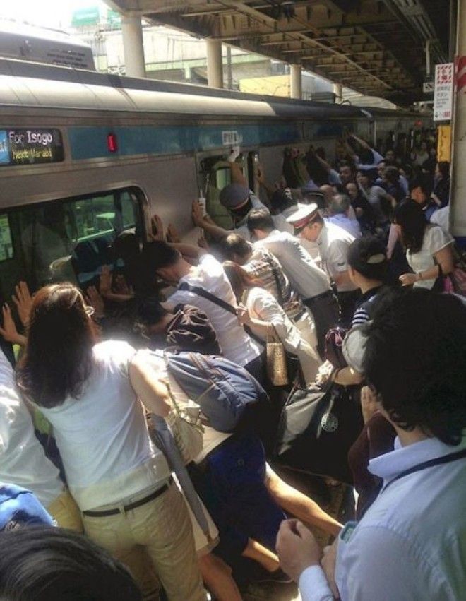 Люди вместе поднимают поезд чтобы спасти человека застрявшего между вагоном и платформой