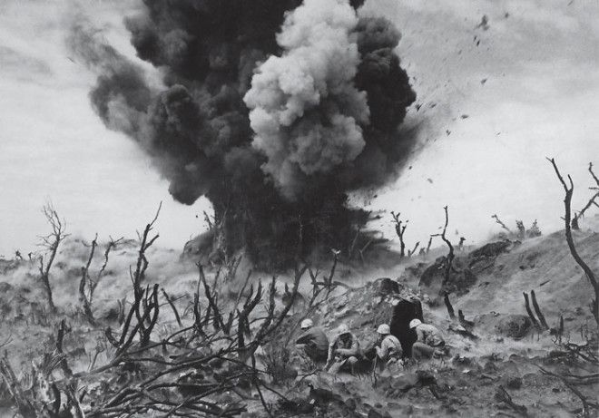 Морские пехотинцы укрываются от огня на вершине холма на Иводзиме в марте 1945 года